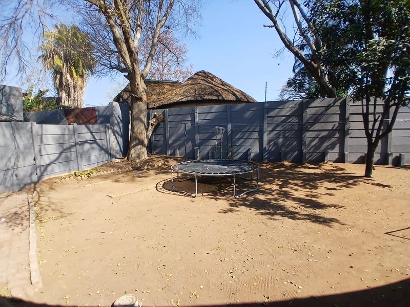 A spacious outdoor garden area featuring a precast concrete boundary wall and mature trees, offering a blank canvas for landscaping improvements.