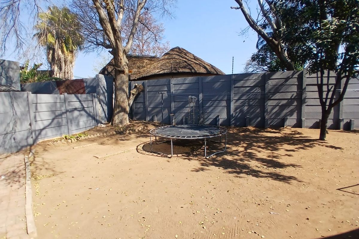 A spacious outdoor garden area featuring a precast concrete boundary wall and mature trees, offering a blank canvas for landscaping improvements.