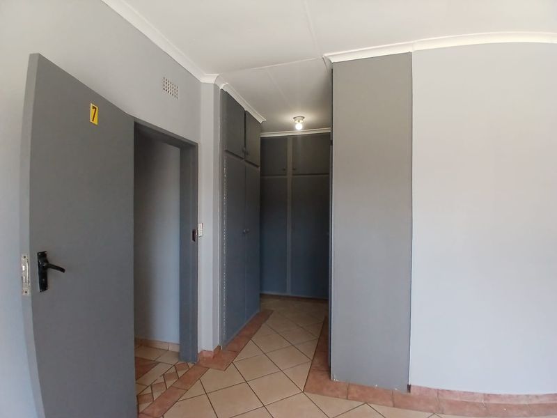 A functional hallway featuring built-in storage cupboards, neutral wall finishes, and ceramic floor tiling.