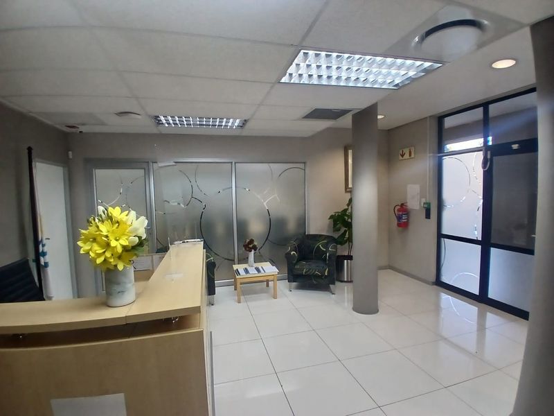 Professional office reception area featuring a built-in reception desk, frosted glass partitions, and bright ceramic floor tiles with recessed lighting.