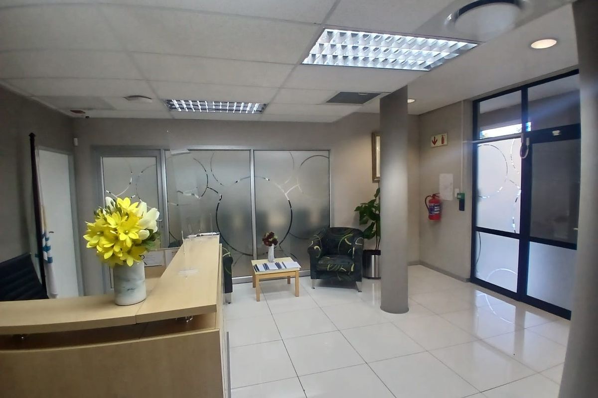Professional office reception area featuring a built-in reception desk, frosted glass partitions, and bright ceramic floor tiles with recessed lighting.