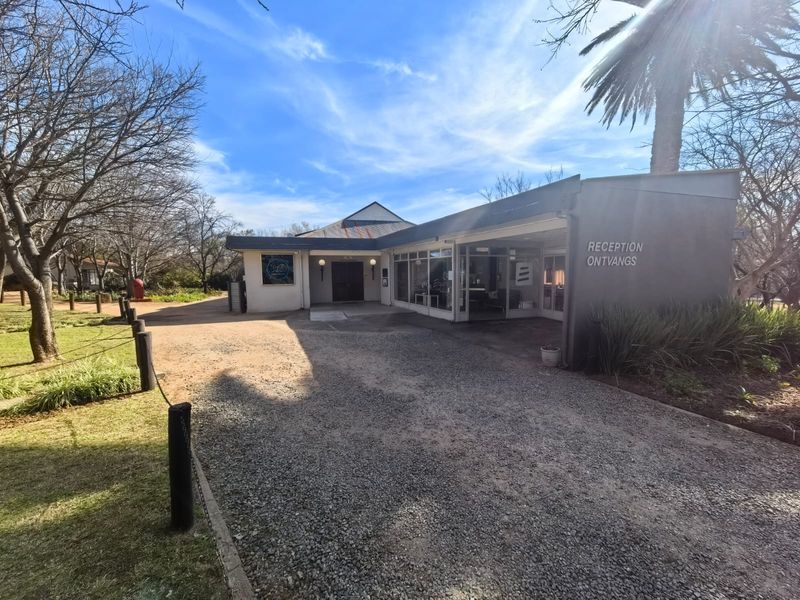 Front exterior view of the business premises featuring a gravel driveway, reception entrance, and established garden surroundings.