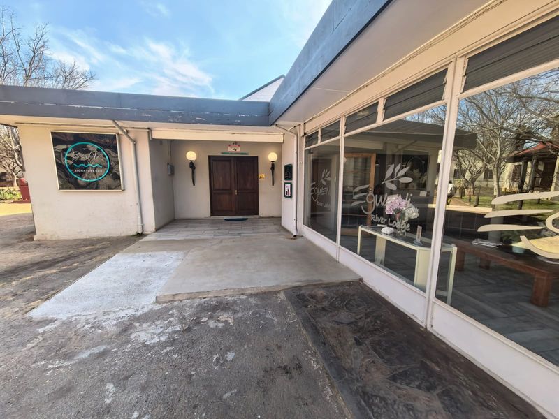 Front entrance of the business premises featuring double wooden doors, large glass display windows, and a covered walkway with exterior lighting.
