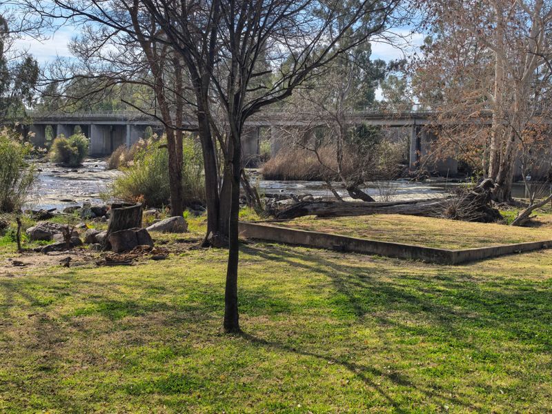 Scenic view of a river and concrete bridge from the property grounds, featuring mature trees and natural landscaping.