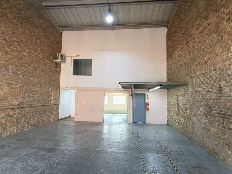 Spacious industrial utility area featuring exposed brick walls, concrete flooring, and high ceilings, suitable for storage or workshop use.