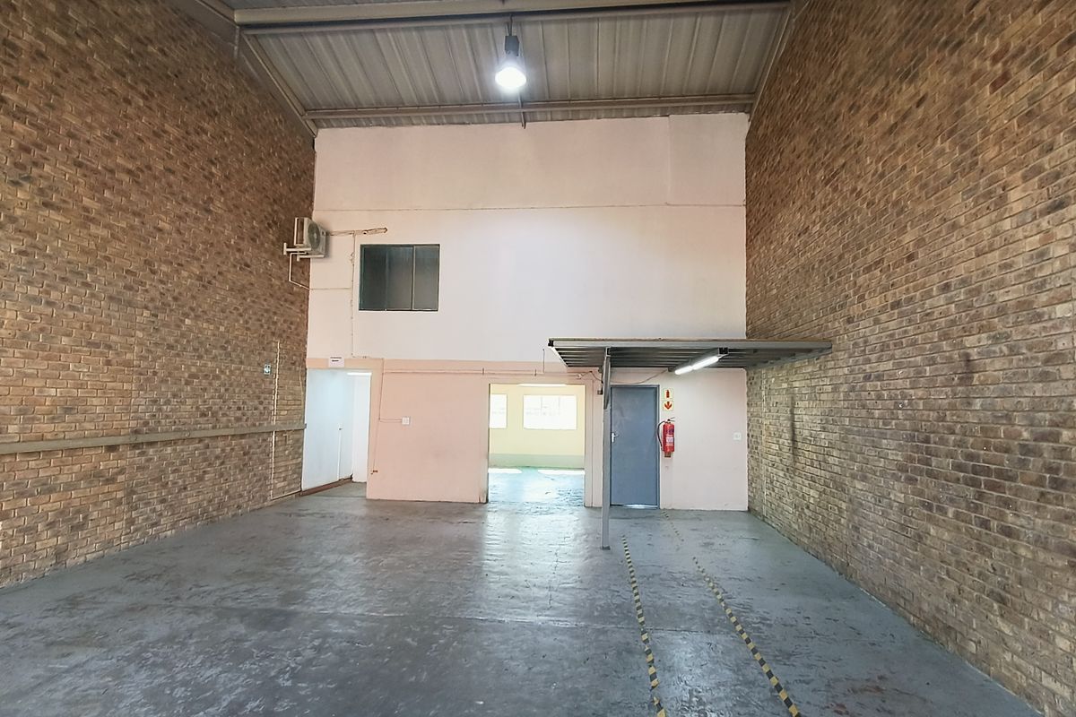 Spacious industrial utility area featuring exposed brick walls, concrete flooring, and high ceilings, suitable for storage or workshop use.