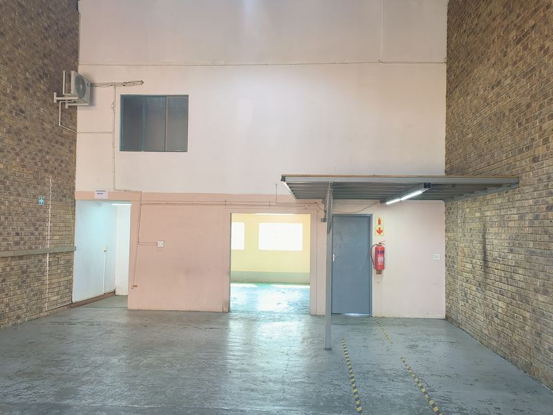 Spacious industrial utility area featuring exposed brick walls, concrete flooring, and integrated lighting, suitable for storage or workshop use.