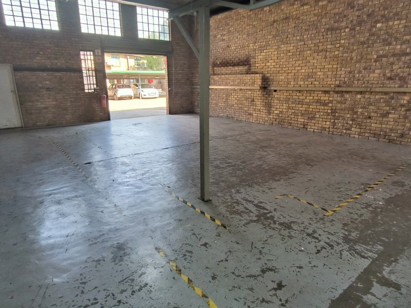 Spacious industrial utility area featuring exposed brick walls, high-level steel-framed windows, and a durable painted concrete floor with safety markings.