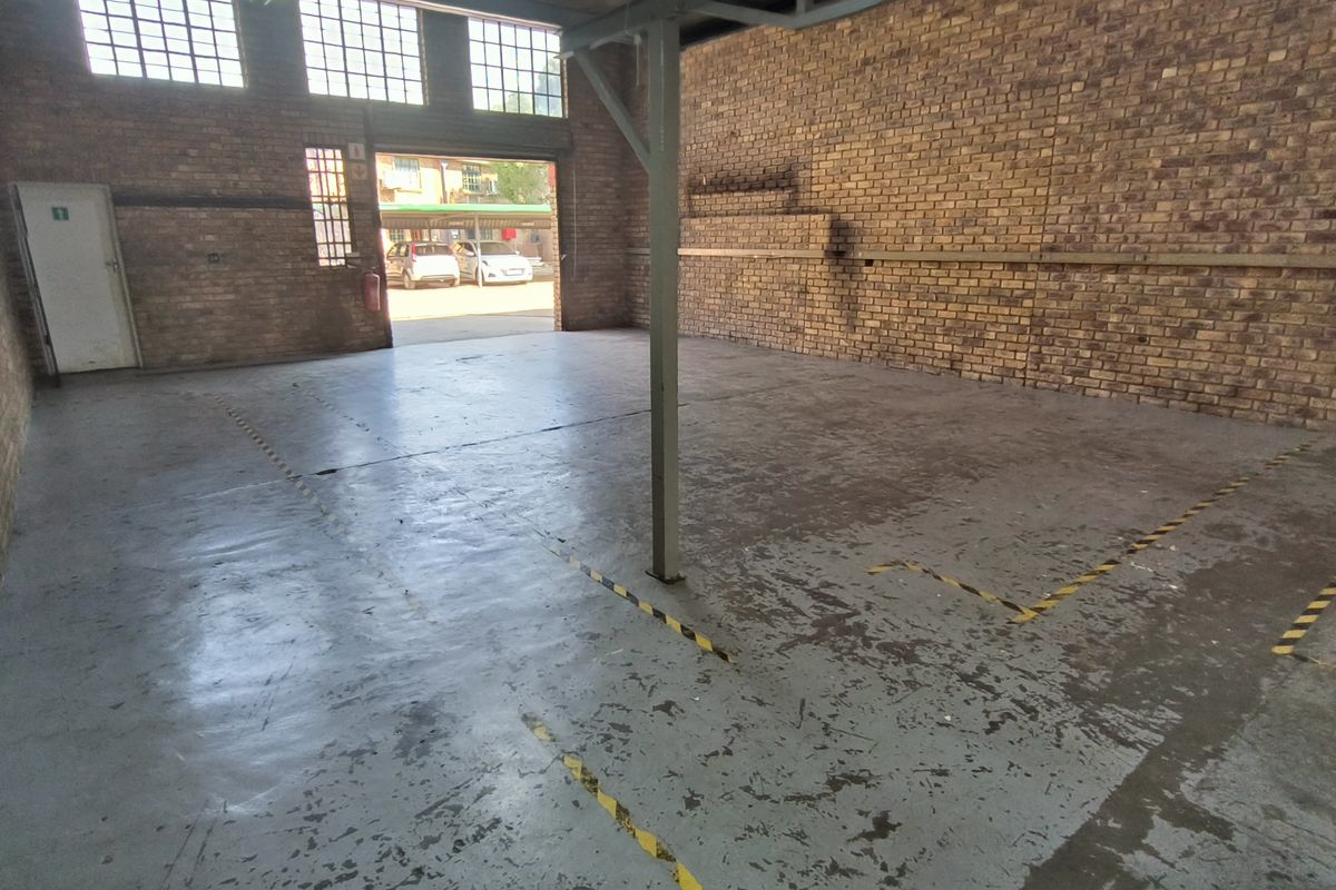 Spacious industrial utility area featuring exposed brick walls, high-level steel-framed windows, and a durable painted concrete floor with safety markings.