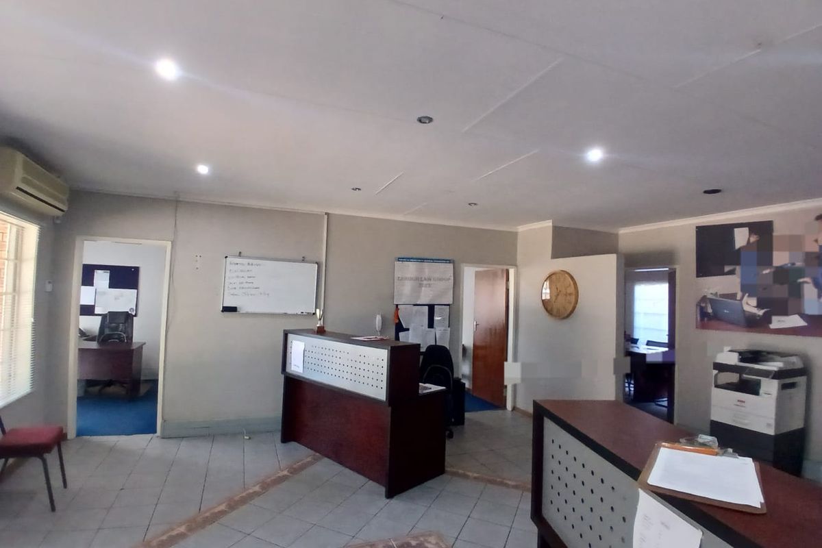 A functional office reception area featuring tiled flooring, recessed lighting, and a built-in reception desk, providing a professional entry point for the workspace.