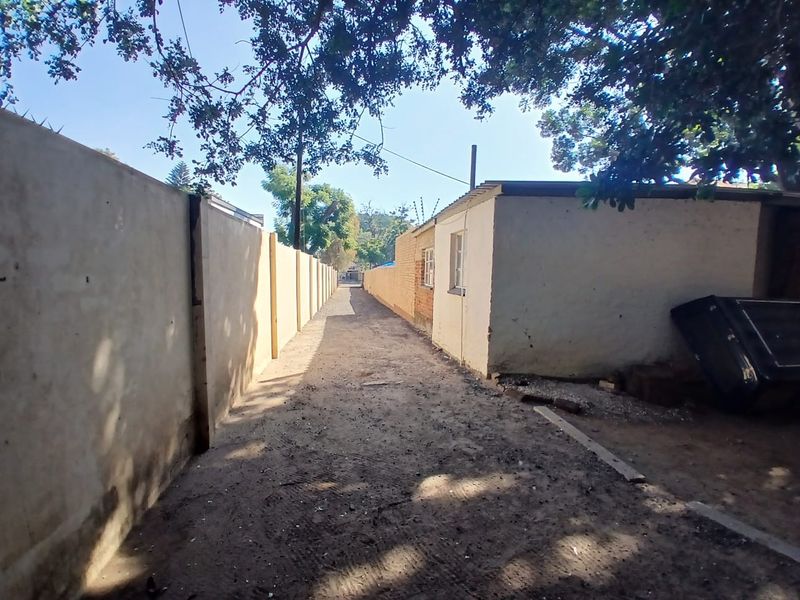 A narrow exterior side passage featuring perimeter walls with electric fencing and an external window view of the office property.