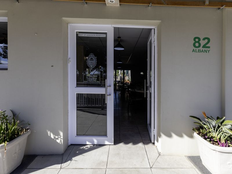 The front entrance of the restaurant features a glass panel door, tiled flooring, and clear building signage.