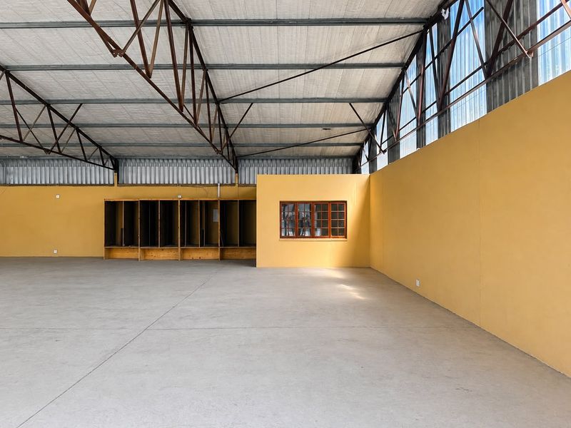 Spacious industrial utility area featuring exposed steel roof trusses, polished concrete flooring, and built-in wooden storage lockers.