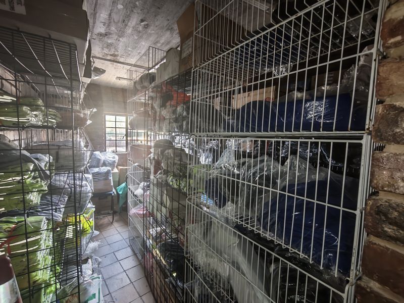 A utilitarian storage room featuring industrial wire shelving, tiled flooring, and exposed brick walls, suitable for inventory or stock management.