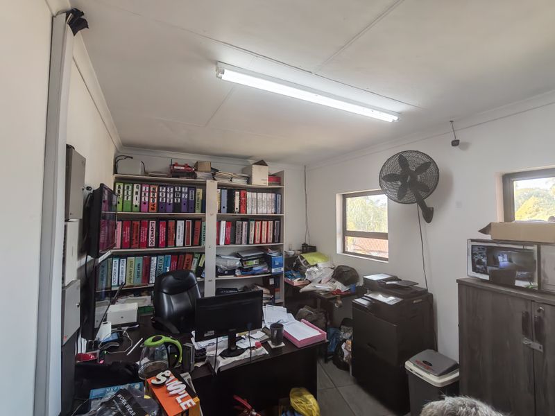 A functional office space featuring tiled flooring, wall-mounted ventilation, and overhead fluorescent lighting, suitable for administrative or business operations.