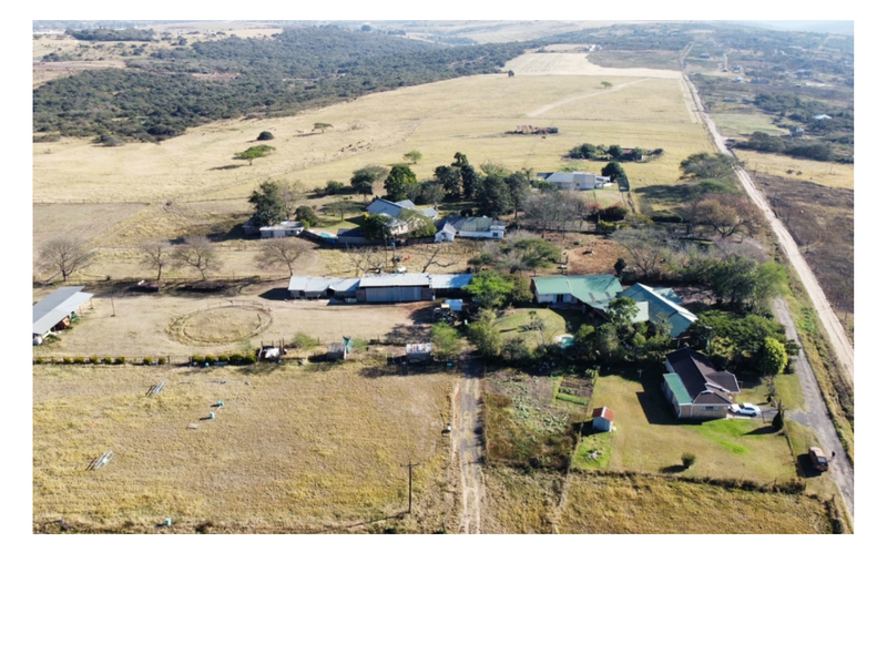 Aerial view of a large commercial vacant land property featuring multiple outbuildings, a main dwelling, and extensive open grazing or development space.