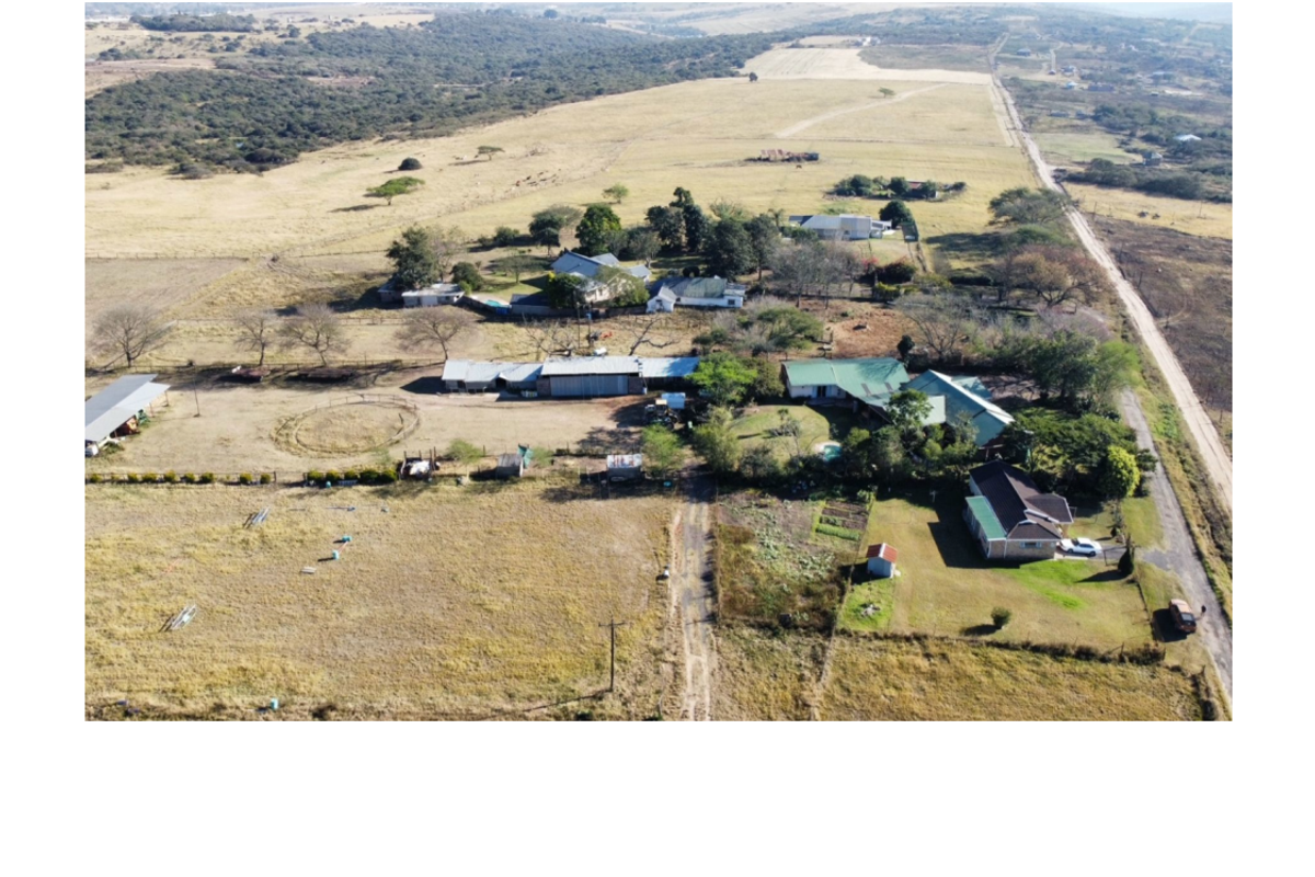 Aerial view of a large commercial vacant land property featuring multiple outbuildings, a main dwelling, and extensive open grazing or development space.