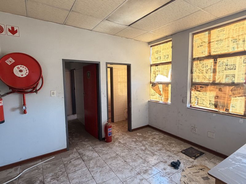 Industrial utility space featuring tiled flooring, suspended ceiling, and essential fire safety equipment, including a hose reel and extinguisher.