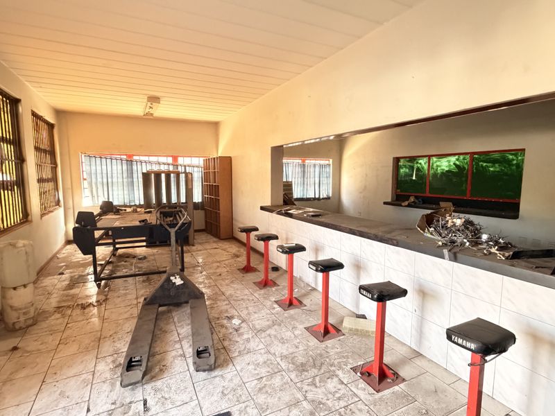 Industrial bar area featuring a built-in counter, tiled flooring, and security window bars, requiring maintenance and cosmetic updates to improve the space.