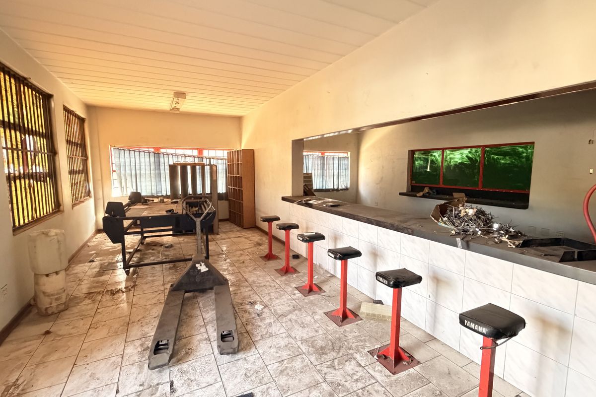 Industrial bar area featuring a built-in counter, tiled flooring, and security window bars, requiring maintenance and cosmetic updates to improve the space.