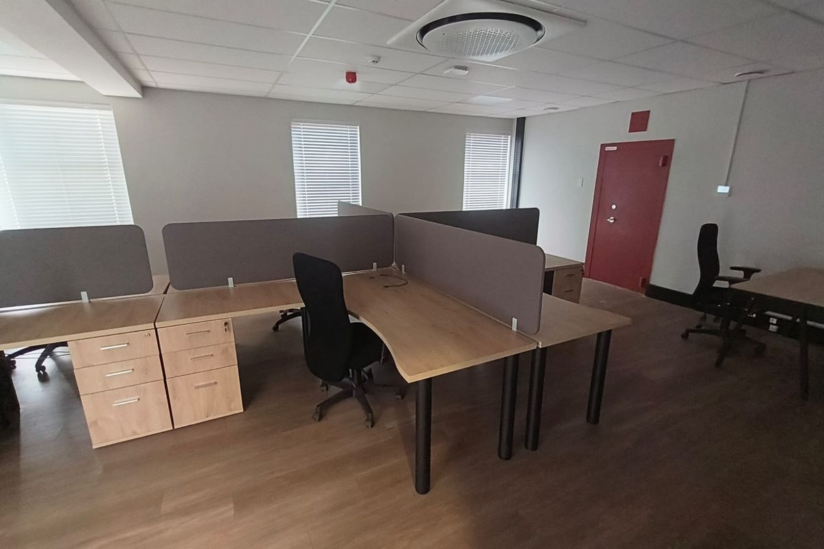 A functional office space featuring a suspended ceiling with integrated air conditioning, laminate flooring, and multiple windows with venetian blinds.