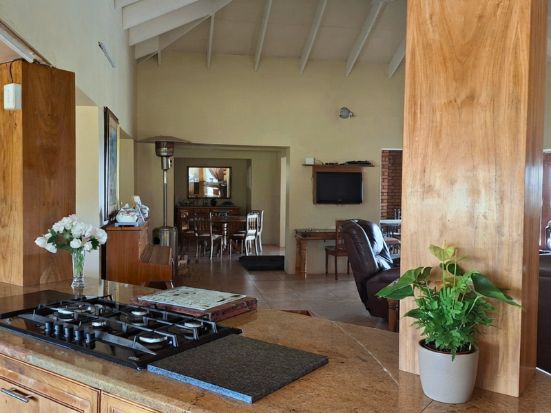 Spacious open-plan living area featuring a kitchen with granite countertops, gas hob, and high vaulted ceilings with exposed beams.