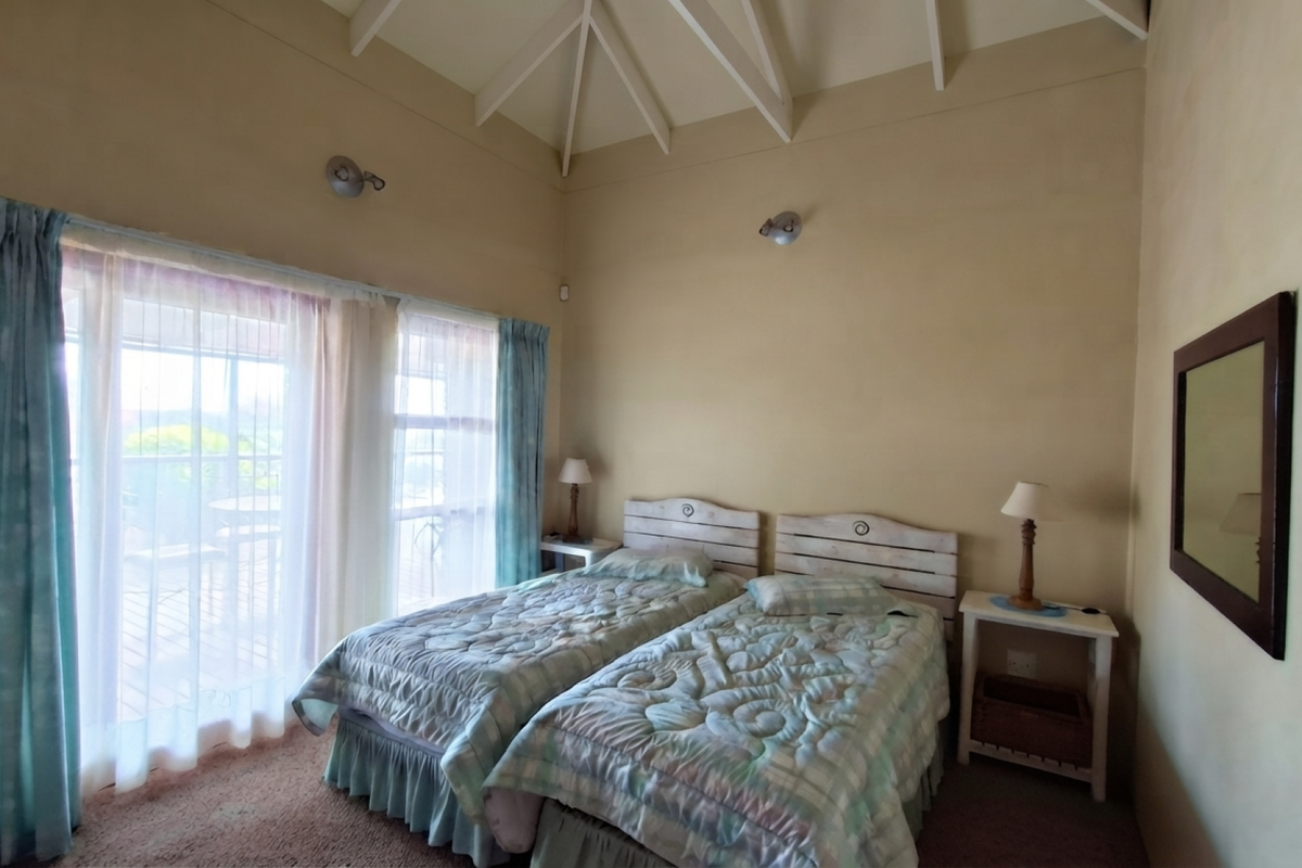 A bedroom featuring a high vaulted ceiling with exposed rafters and large sliding glass doors that provide natural light and access to the outdoors.