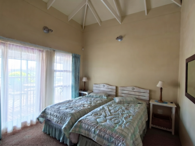 A bedroom featuring a high vaulted ceiling with exposed rafters and large sliding glass doors that provide natural light and access to the outdoors.