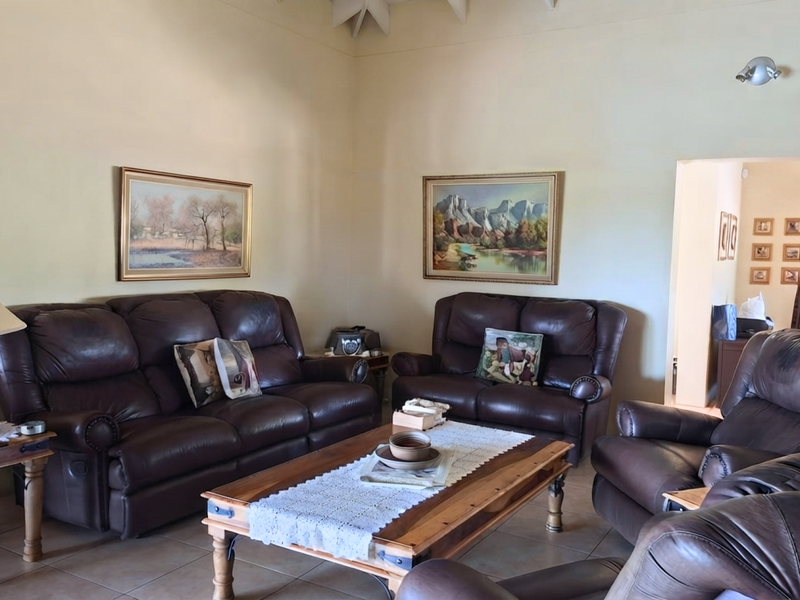 A spacious living room featuring high vaulted ceilings, neutral wall finishes, and durable tiled flooring, offering a comfortable and well-lit seating area.