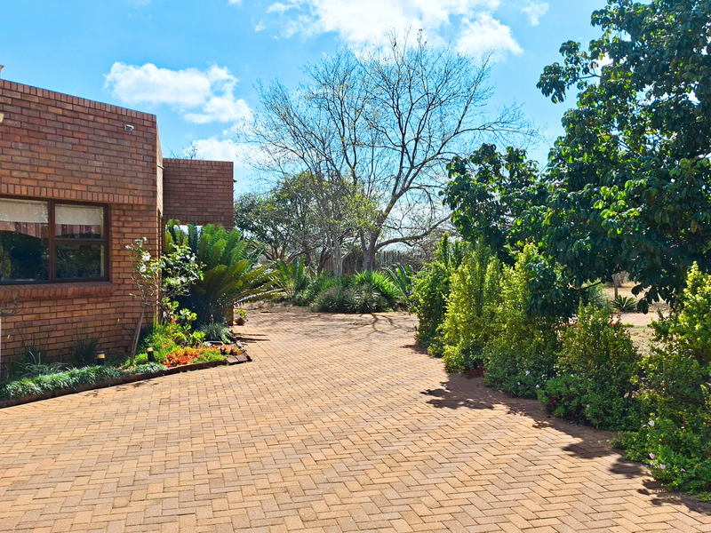 A well-maintained face-brick exterior featuring a paved driveway and established garden landscaping, showcasing the property's curb appeal.
