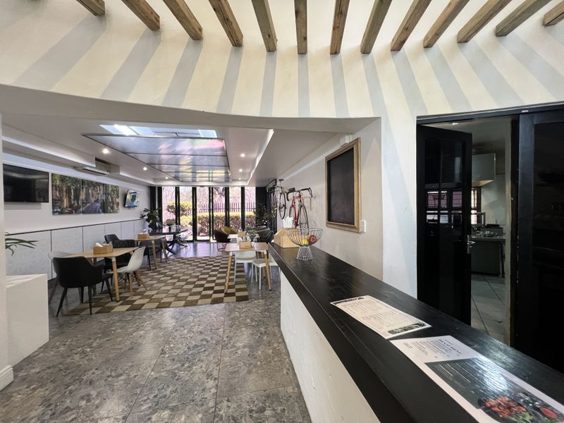 Spacious open-plan office or commercial area featuring exposed timber ceiling beams, a built-in service counter, and large bi-fold doors leading to the exterior.
