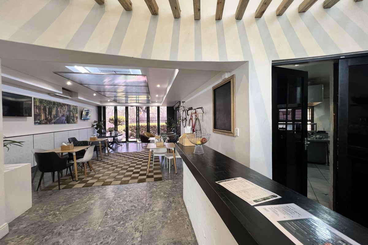 Spacious open-plan office or commercial area featuring exposed timber ceiling beams, a built-in service counter, and large bi-fold doors leading to the exterior.
