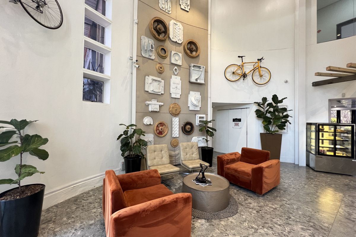 A spacious office reception area featuring high ceilings, terrazzo flooring, and a unique decorative feature wall with integrated vertical windows.