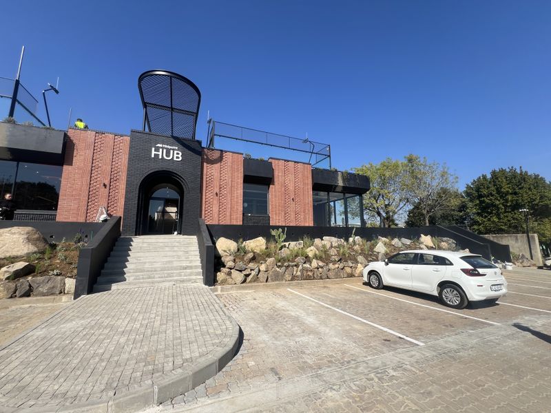 Modern office building exterior featuring a striking brick facade, stone landscaping, and a paved parking area with a prominent entrance.
