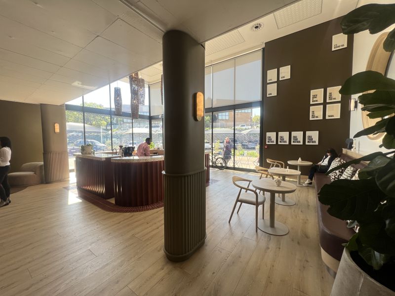 Modern open-plan office lobby or cafe area featuring floor-to-ceiling windows, contemporary service counter, and high-quality finishes throughout.