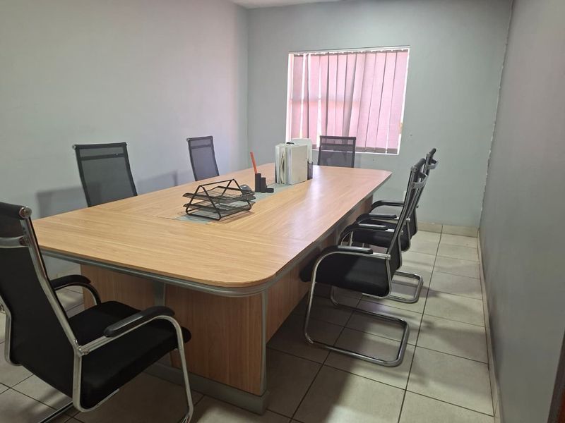 A functional office space featuring ceramic floor tiles and vertical window blinds, suitable for a professional meeting or workspace environment.