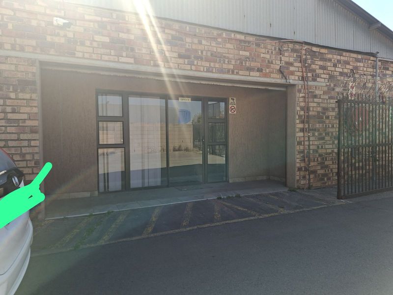 Industrial office entrance featuring a brick facade, aluminium glass door, and security surveillance system with adjacent gated access.