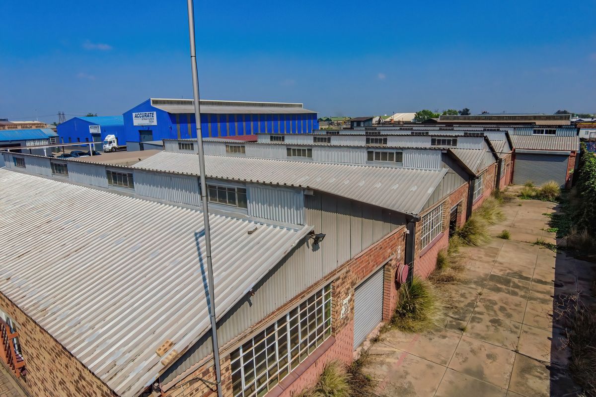 Aerial view of an industrial warehouse complex featuring corrugated metal roofing, brick facades, and paved yard space with roller shutter access.