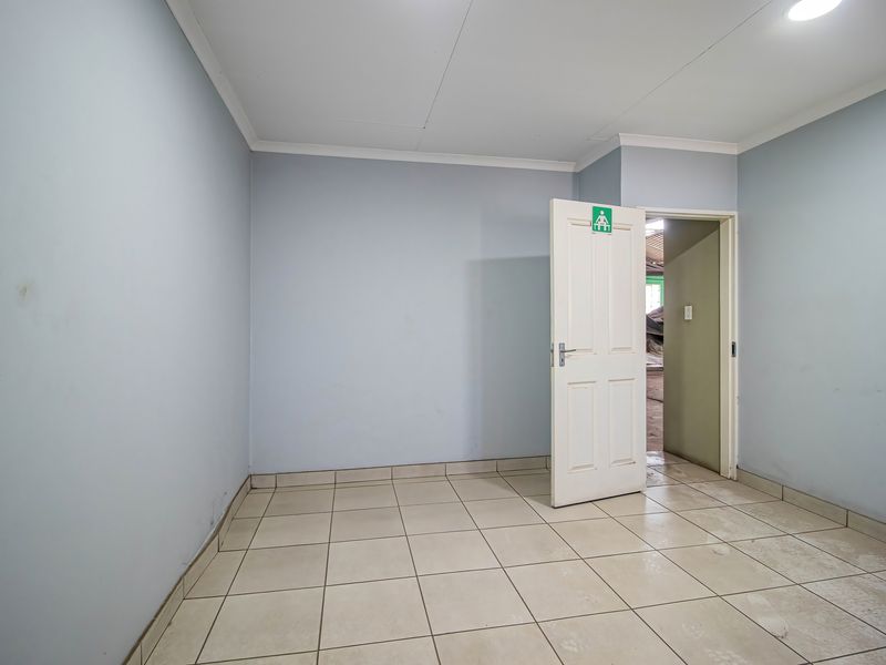 A clean, empty utility space featuring tiled flooring, recessed lighting, and neutral wall finishes, suitable for various industrial or storage purposes.