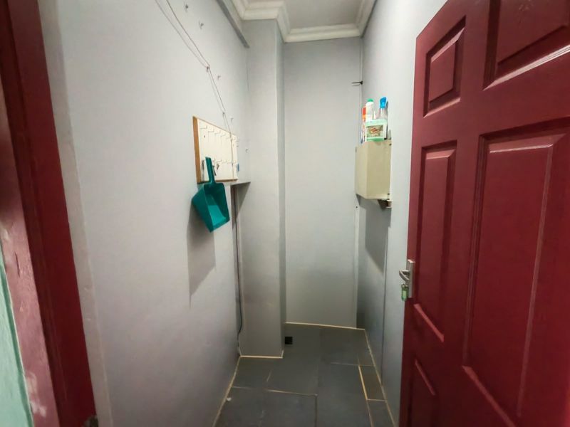 A functional hallway space featuring tiled flooring and a painted interior door, providing a clean and simple transition area within the apartment.