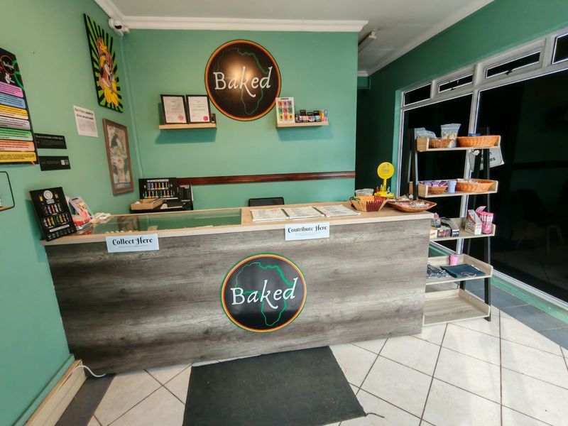 A commercial retail service counter area featuring a wood-look finish, tiled flooring, and large aluminium-framed windows.