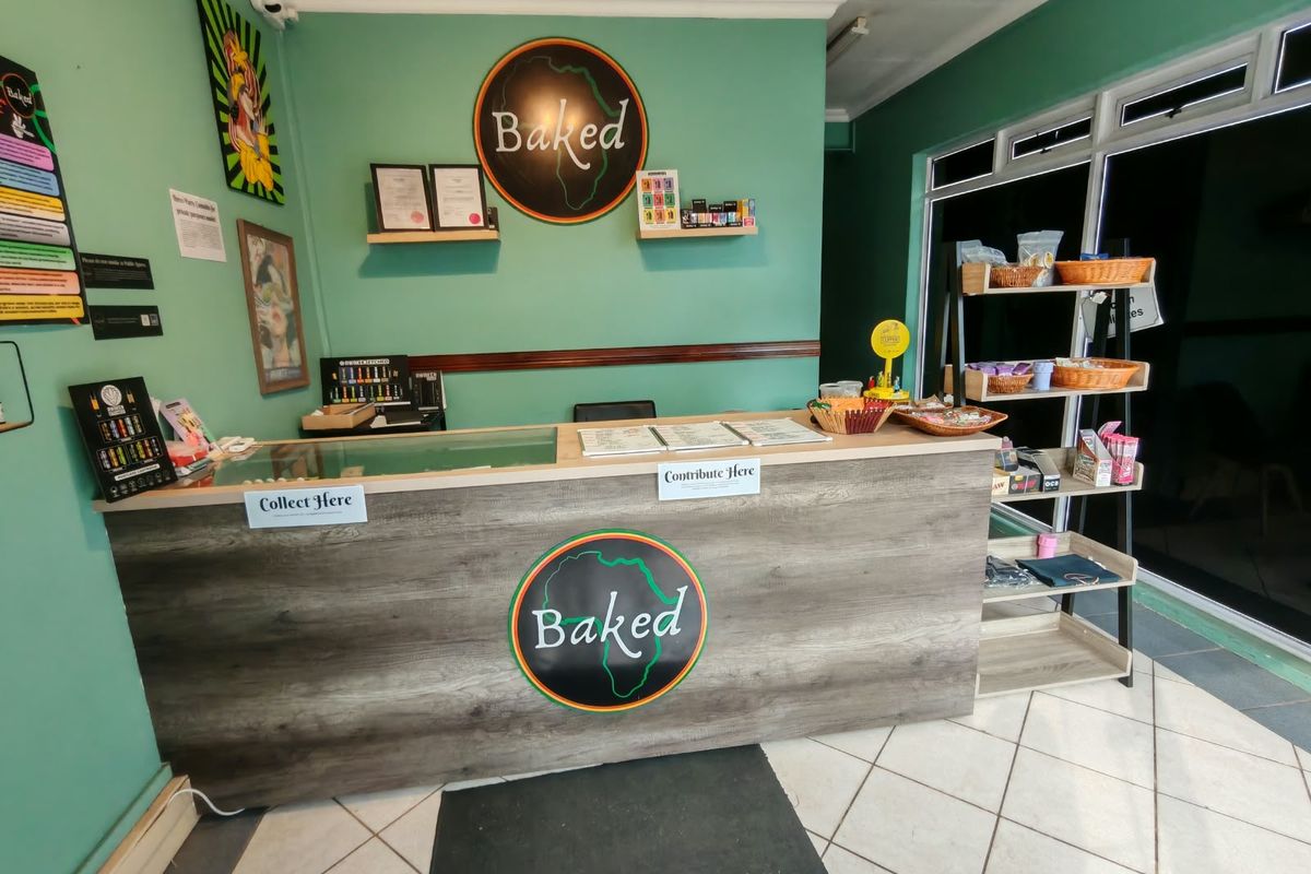 A commercial retail service counter area featuring a wood-look finish, tiled flooring, and large aluminium-framed windows.