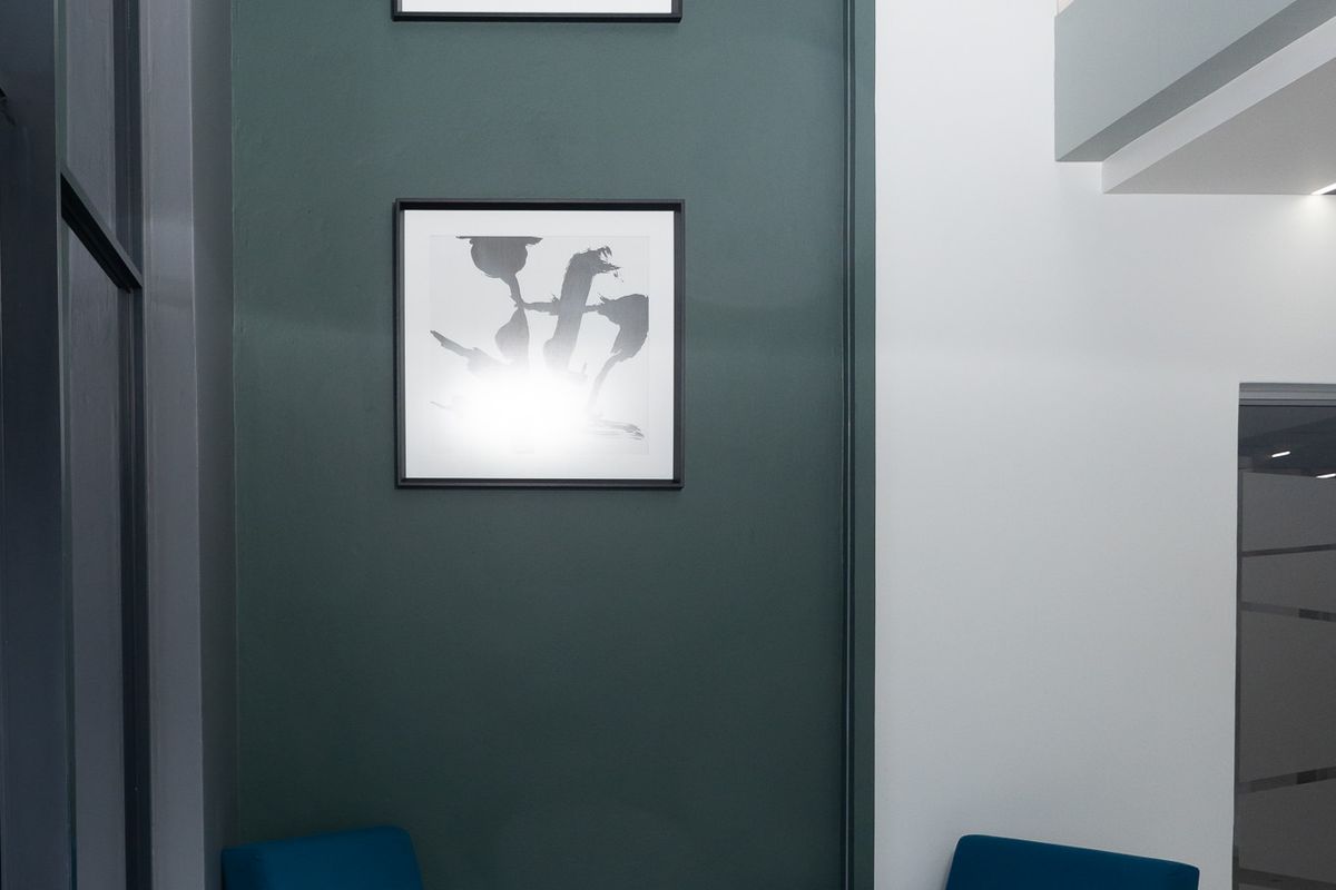 Modern double-volume office entrance foyer featuring a striking dark green accent wall, tiled flooring, and a sleek stainless steel balustrade.