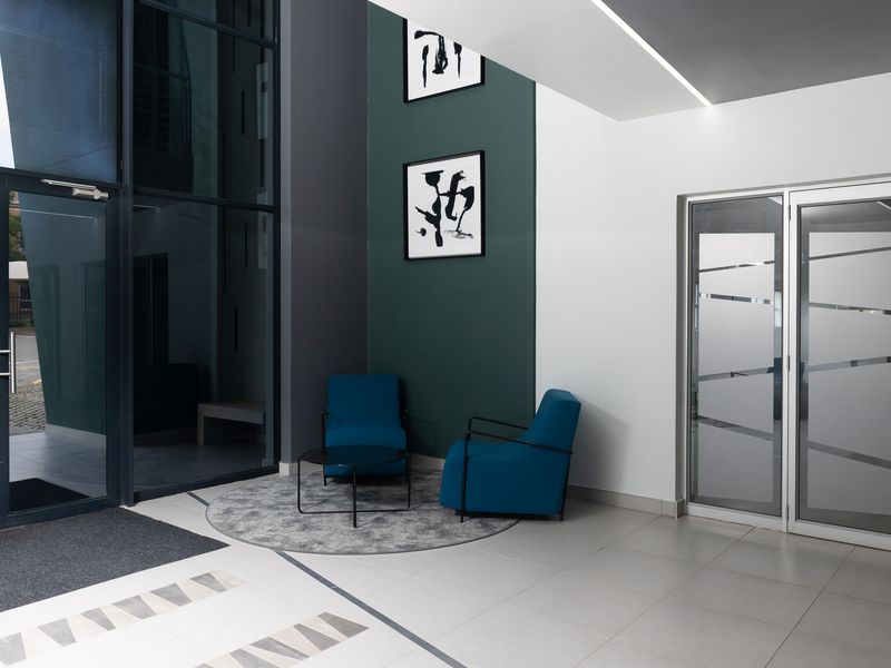 Modern office building entrance featuring high ceilings, large glass facade, tiled flooring, and a professional, contemporary aesthetic.