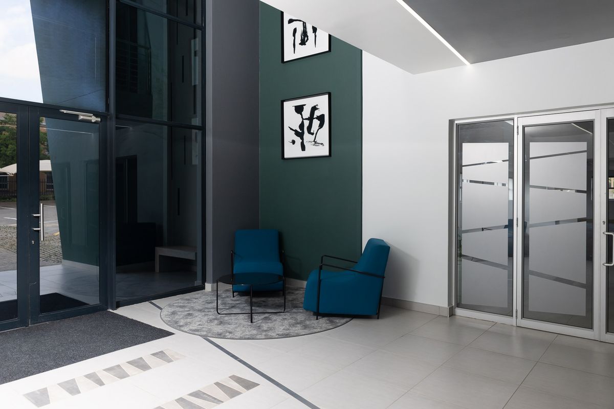 Modern office building entrance featuring high ceilings, large glass facade, tiled flooring, and a professional, contemporary aesthetic.