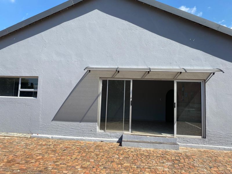 Rear exterior view of the property featuring a paved patio area, sliding glass doors with a protective awning, and a single step entrance.