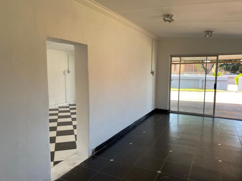 An empty living area featuring dark ceramic floor tiles, coved ceilings, and a large sliding glass door providing access to the exterior.