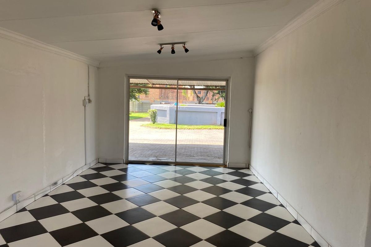 An empty living room featuring a black and white checkered tile floor, coved ceilings, and a sliding glass door providing access to the exterior.