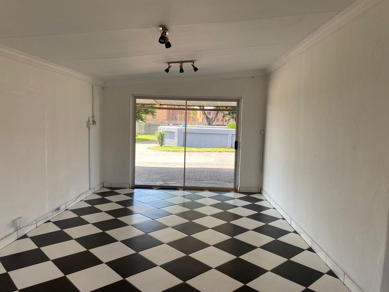 An empty living room featuring a black and white checkered tile floor, coved ceilings, and a sliding glass door providing access to the exterior.