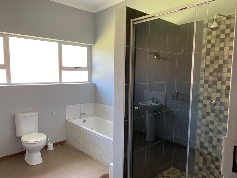 A functional bathroom featuring a built-in bathtub, a separate shower enclosure with tiled walls, a pedestal basin, and a toilet.